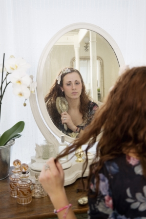 Young woman brushing her hair in front of mirrorの写真素材