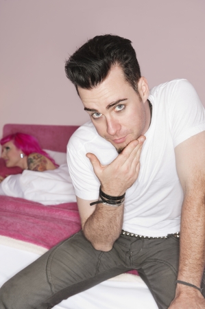 Portrait of man posing while woman lying on bed in the backgroundの写真素材