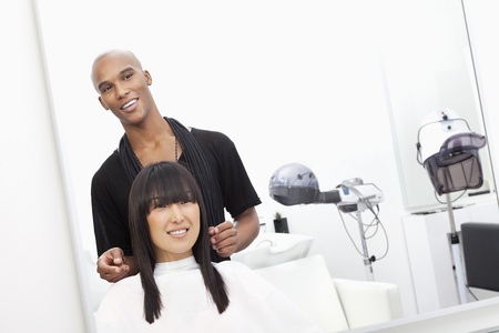 Hairstylist with female customer at beauty salonの写真素材