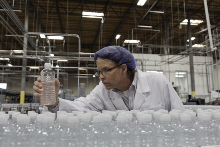 Quality control worker checking bottled water at bottling plantの写真素材