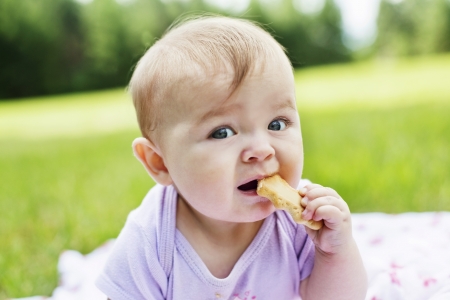 Close-up of infant girl eating biscuitの写真素材