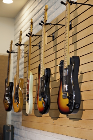 Five electric guitars hanging on display rack in store for saleの写真素材