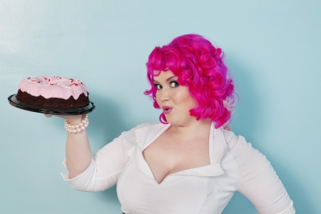 Portrait of happy woman showing cake over colored backgroundの写真素材