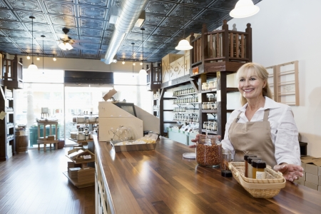 Happy senior female spice merchant standing at counter while looking away in storeの写真素材