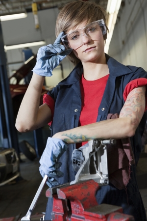 Portrait of a young female mechanic wearing protective eyewear in garageの写真素材