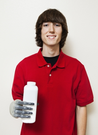 Portrait of a happy young man holding bottle with prosthetic hand over gray backgroundの写真素材