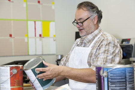 Happy mature sales clerk reading instructions paint can in hardware storeの写真素材
