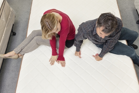 Friends sitting on mattress in furniture storeの写真素材