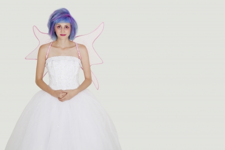 Portrait of beautiful young woman dressed as angel with dyed hair against gray backgroundの写真素材