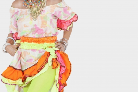 Midsection of senior woman in Brazilian costume over gray background