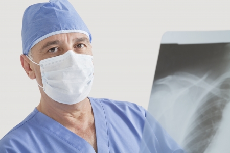Portrait of senior male surgeon examining x-ray over gray backgroundの写真素材