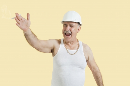 Senior male constructor shouting over yellow backgroundの写真素材