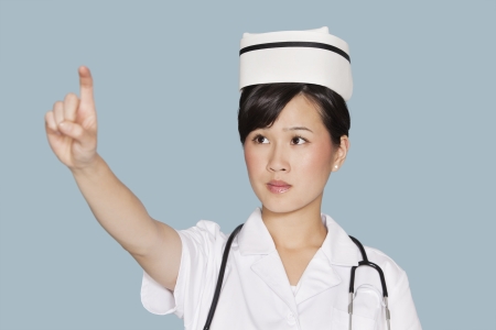 Young female doctor using transparent screen over light blue backgroundの写真素材
