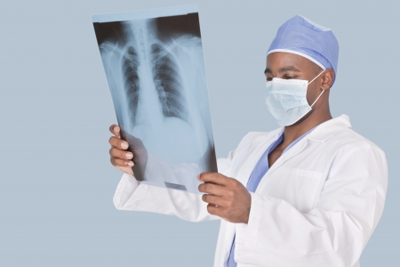 Male surgeon analyzing x-ray report over light blue background