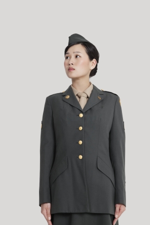 Female US military officer standing in attention as she looks away over gray backgroundの写真素材
