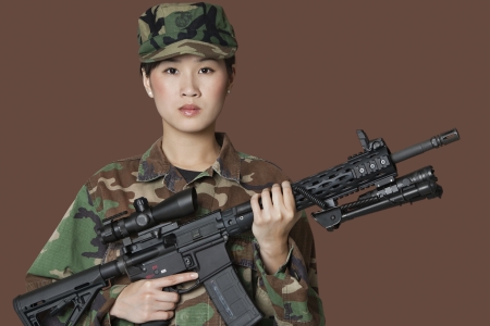 Portrait of beautiful young US Marine Corps soldier with M4 assault rifle over brown backgroundの写真素材