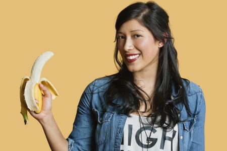 Portrait of a young woman with banana over colored backgroundの写真素材
