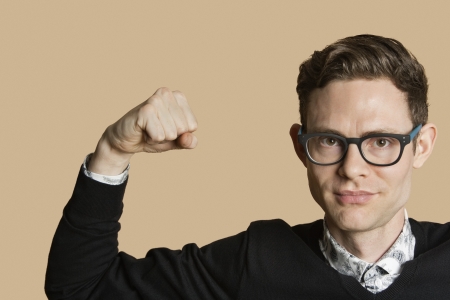 Portrait of a mid adult man flexing muscles over colored backgroundの写真素材