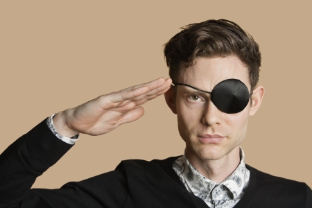 Portrait of a man wearing eye patch saluting over colored backgroundの写真素材