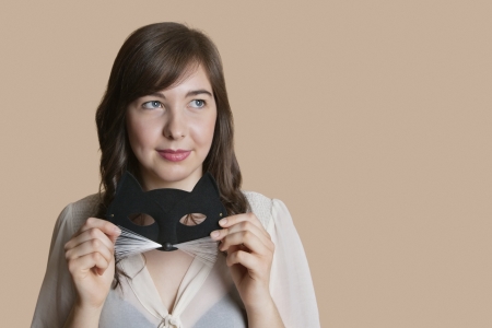 Young woman holding eye mask while looking away over colored backgroundの写真素材