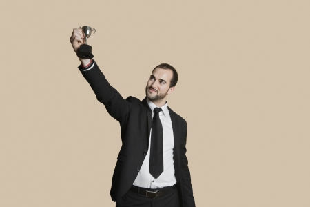 Happy young man raising winning trophy over colored backgroundの写真素材