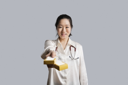 Portrait of a young female doctor giving medicine boxesの写真素材