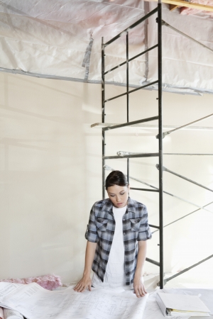 Mid adult female contractor looking at blueprintsの写真素材