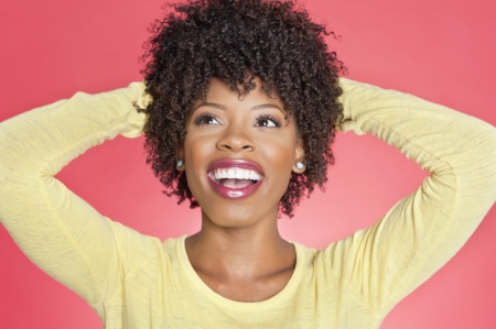 Cheerful African American looking up with hands behind head over colored backgroundの写真素材