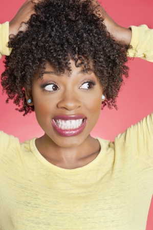 African American looking sideways with hands in hair over colored backgroundの写真素材