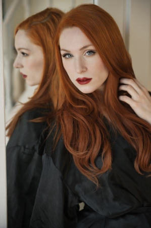Portrait of a beautiful young woman in robe with hand in hairの写真素材