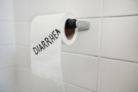 Close-up of toilet paper roll with diarrhea written in bathroom