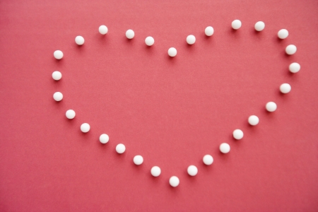 Close-up of push pins forming heart shaped over pink foregroundの写真素材