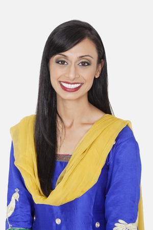 Portrait of pretty Indian woman in traditional wear smiling against gray background