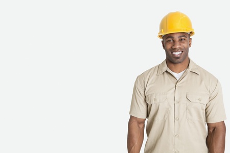 Portrait of happy young African man wearing yellow hard hat helmet over gray backgroundの写真素材
