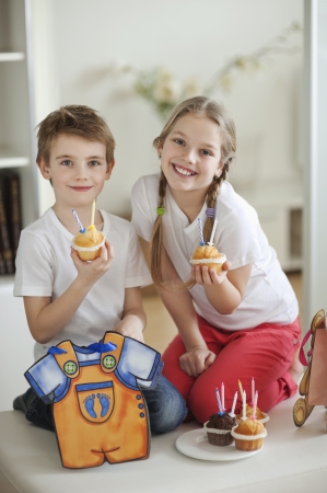 Portrait of little boy and girl with cup cakesの写真素材