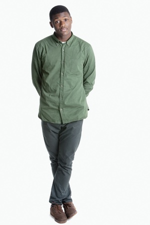 Portrait of a young African American man standing with legs crossed over gray backgroundの写真素材
