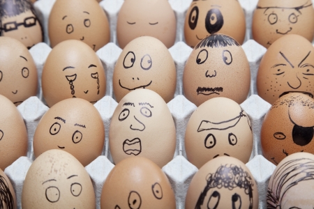 Funny faces on painted on brown eggs arranged in cartonの写真素材