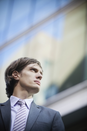 Low angle view of young businessman looking away with building in the backgroundの写真素材