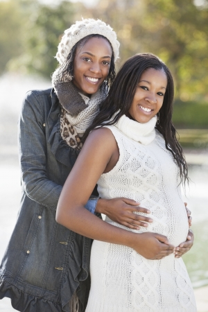Portrait of happy young female friend embracing pregnant woman from behindの写真素材