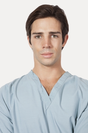 Portrait of confident young man in surgical scrubs over gray backgroundの写真素材