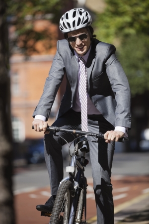 Portrait of happy young businessman riding bicycleの写真素材