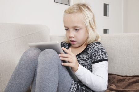 Young girl using digital tablet on sofaの写真素材