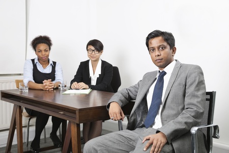 Portrait of Asian male with female colleagues in background at desk in officeの写真素材