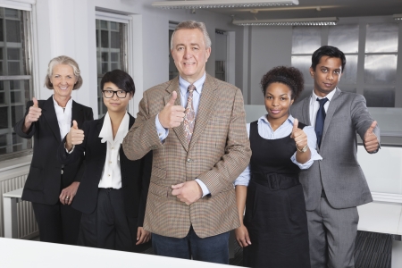 Portrait of multiethnic business group gesturing thumbs up at officeの写真素材