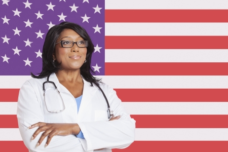 Confident mixed race female surgeon looking away over American flagの写真素材