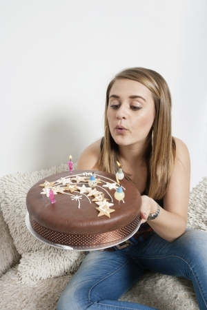 Young woman blowing out candles on birthday cakeの写真素材
