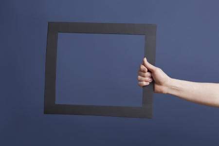 Hand holding frame over blue backgroundの写真素材