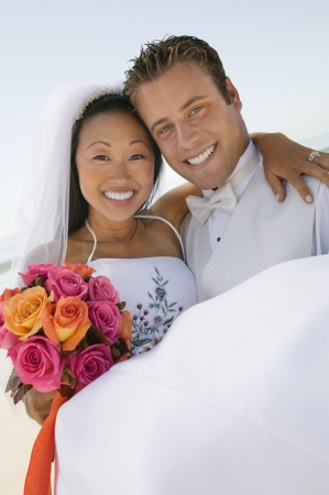Groom carrying bride outdoors (portrait)の写真素材