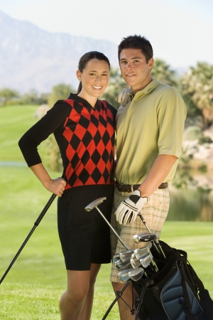 Couple of golfers standing together on golf course (portrait)の写真素材