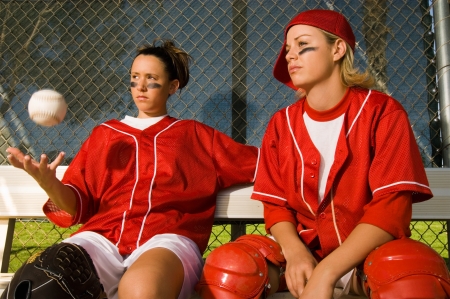 Softball players sitting on bench portraitの写真素材